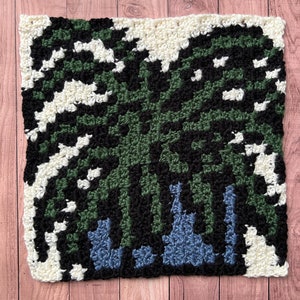 May include: A square crochet pattern with a green, black, and white design. The pattern is made with different colored yarn and has a geometric design.