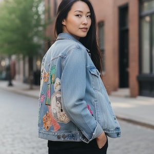 May include: Light blue denim jacket with colorful embroidered patches on the back. The patches feature various designs, including a fox, flowers, and other whimsical elements. The jacket has a classic design with button closures and pockets.