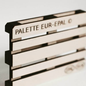 May include: A miniature wooden pallet with the text "PALETTE EUR-EPAL" printed on the top.