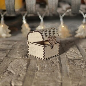 May include: A small, open wooden chest with a heart-shaped clasp. The chest is made of light-colored wood and has a decorative, slotted lid. The heart clasp is intricately carved. The chest is likely for jewelry or small keepsakes.