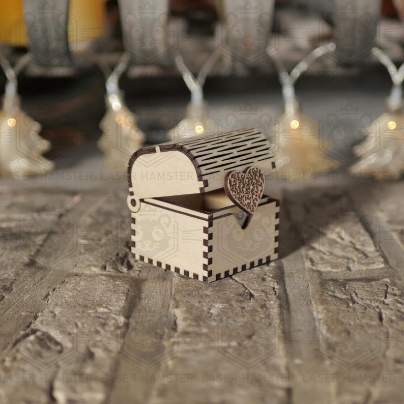 May include: A small, open wooden chest with a heart-shaped clasp. The chest is made of light-colored wood and has a decorative, slotted lid. The heart clasp is intricately carved. The chest is likely for jewelry or small keepsakes.