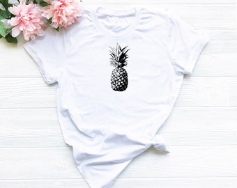 Pode incluir: Camiseta branca com um gráfico de abacaxi preto e branco.