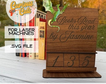 May include: A wooden book-reading calendar with the text "Books Read this year by Jasmine." A green dragon is attached to the side. The calendar displays the numbers 1, 3, and 5. The image also includes the text "FOR LASER MACHINES" and ".SVG FILE."
