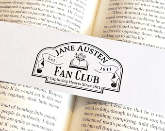 May include: A white bookmark with a black and white illustration of a book and the text "Jane Austen Fan Club, Capturing Hearts Since 1811".
