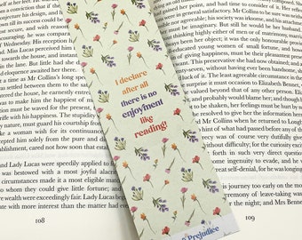 Könnte beinhalten: Ein florales Lesezeichen mit weißem Hintergrund und einem Zitat in schwarzem Text, das lautet: "Ich erkläre, dass es nach allem keinen Genuss gibt wie das Lesen!"