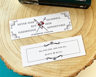 May include: Two white bookmark designs with black text and decorative flourishes. The top bookmark features a quote from "The Three Musketeers" by Alexandre Dumas: "Never fear but hazardous quarrels, seek adventures." The bottom bookmark features the quote: "All for one, one for all." with the words "Quote & Quill" below.