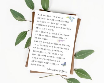 Könnte beinhalten: Eine weiße Karte mit einem Zitat über einen Sommer, der nie vergessen werden sollte. Das Zitat ist in schwarzer Schrift mit lila und blauen Blumenillustrationen geschrieben. Die Karte liegt auf einer braunen Oberfläche mit grünen Blättern.