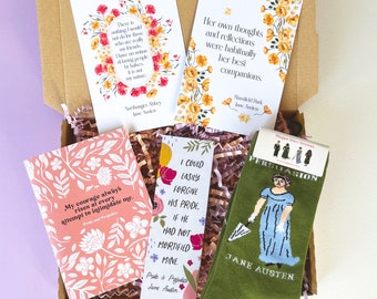 May include: A gift box filled with Jane Austen themed items, including a pair of green socks with a Jane Austen quote and a character from the novel Persuasion, a bookmark with a quote from Pride and Prejudice, and two cards with quotes from Northanger Abbey and Mansfield Park.
