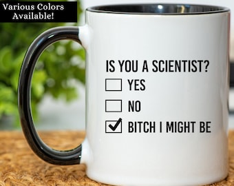 May include: White coffee mug with a black rim and handle. The mug has black text that reads "IS YOU A SCIENTIST?" with a check box next to the text "YES", "NO", and "BITCH I MIGHT BE". The check box next to "BITCH I MIGHT BE" is checked.