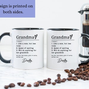 Pu&ograve; includere: Due tazze in ceramica bianca con manici e bordi neri. Le tazze presentano la parola "Grandma" con un simbolo a cuore, una definizione e il nome "Dorothy". &Egrave; visibile anche il testo "Design is printed on both sides".