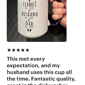 May include: White ceramic mug with a blue handle. The mug has black text that reads "Boyfriend Est. 2013, Fianc&eacute; Est. 2020, Husband Est. 2022, Dad Est. 2023".