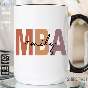 Może przedstawiać: Biały kubek ceramiczny z czarnym uchwytem. Kubek ma kolorowy wz&oacute;r z napisem "MBA emily". Kubek nadaje się do mycia w zmywarce i do mikrofal&oacute;wki.