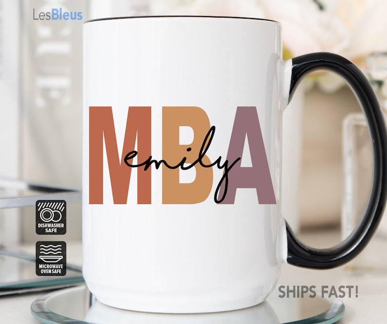 Może przedstawiać: Biały kubek ceramiczny z czarnym uchwytem. Kubek ma kolorowy wz&oacute;r z napisem "MBA emily". Kubek nadaje się do mycia w zmywarce i do mikrofal&oacute;wki.