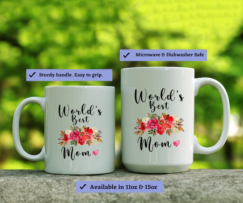 May include: Two white ceramic mugs with black text and floral designs. The larger mug reads "World's Best Mom" and the smaller mug reads "World's Best Mom". Both mugs have a pink heart design. The mugs are microwave and dishwasher safe.