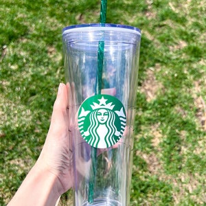May include: A clear plastic tumbler with a green lid and a green straw. The tumbler has a Starbucks logo on the side.