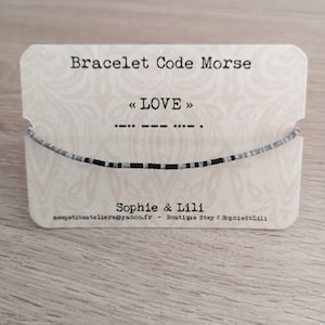 Peut inclure: Une carte blanche avec du texte noir qui dit "Bracelet Code Morse" et "< LOVE >" avec un bracelet en perles noir et blanc sur la carte. La carte comprend également le texte "Sophie & Lili" et "nespetitsateliers@yahoo.fr - Boutique Etsy: SophieStLili".