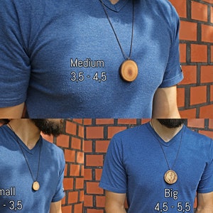Może przedstawiać: Trzech mężczyzn w niebieskich koszulach z drewnianymi wisiorkami o r&oacute;żnych rozmiarach na czarnym sznurku. Wisiorki są oznaczone jako "Mały 2,5 - 3,5", "Średni 3,5 - 4,5" i "Duży 4,5 - 5,5".