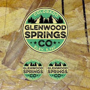 May include: Three round stickers with a green and yellow design. The stickers feature a mountain range with trees, the text "COLORADO GLENWOOD SPRINGS CO" and the elevation "ELEV. 5,761'"