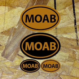 May include: Four oval stickers with the word "MOAB" in black lettering. The stickers are in different sizes and have a brown or black background.
