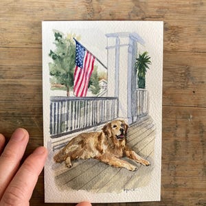 May include: Watercolor painting of a golden retriever dog lying on a wooden deck. An American flag waves in the background, along with a white porch and green trees. The artwork is signed "Bryce".