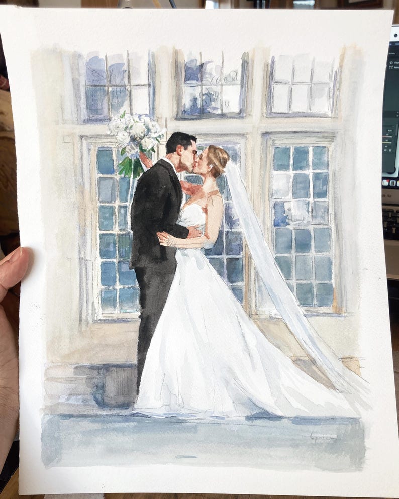 May include: Watercolor painting of a wedding couple kissing. The bride wears a white wedding dress and veil, and the groom is in a black tuxedo. A bouquet of white flowers is held by the groom. The background features large windows.