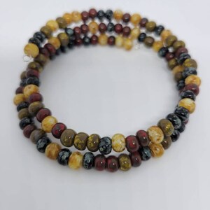 May include: A multi-strand bracelet made of small, round beads in shades of brown, yellow, red, and black.