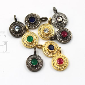 Peut inclure: Plusieurs pendentifs ronds avec des pierres précieuses de différentes couleurs, dont émeraude, rubis, saphir et aigue-marine. Les pendentifs présentent un design détaillé avec de petites pierres d'accentuation, sertis dans du métal doré et argenté.