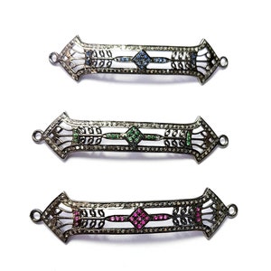 Peut inclure: Trois connecteurs de bijoux en métal argenté avec des motifs complexes. Chaque connecteur présente un espace central en forme de diamant rempli de petites pierres précieuses. Le connecteur supérieur a des pierres précieuses bleues, le connecteur du milieu a des pierres précieuses vertes et le connecteur inférieur a des pierres précieuses roses.