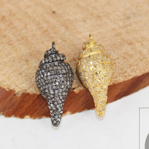 May include: Two shell-shaped pendants, one with black diamonds and one with gold diamonds, on a wooden surface.  GEMCO JEWELRY NEW YORK is printed on a white tag.