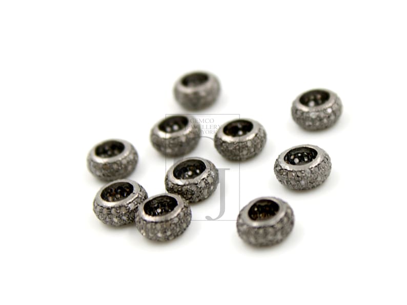 May include: A close-up of ten silver-toned round beads with a pave diamond setting. The beads are scattered on a white surface.