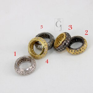 May include: Five gold and silver rings with small diamonds set in the metal. The rings are arranged in a semi-circle on a white surface.
