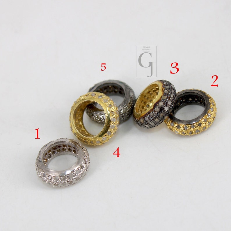 May include: Five gold and silver rings with small diamonds set in the metal. The rings are arranged in a semi-circle on a white surface.