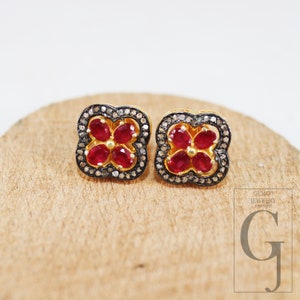 Peut inclure: Une paire de boucles d'oreilles en or de forme carrée avec un motif de fleur de rubis rouge. Les boucles d'oreilles sont serties de petits diamants.