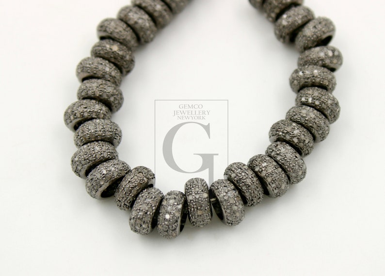 May include: A strand of black rhodium plated silver beads, each bead is encrusted with small diamonds. The beads are round and have a slightly textured surface. The strand is approximately 18 inches long. Gemco Jewellery New York.