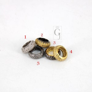 May include: Five silver, gold, and black rings with small diamonds set in the metal. The rings are stacked on top of each other.