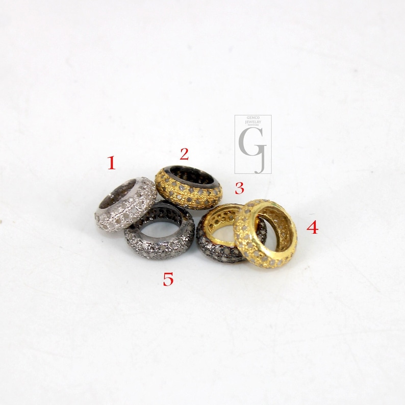May include: Five silver, gold, and black rings with small diamonds set in the metal. The rings are stacked on top of each other.