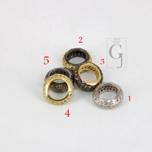 May include: Five silver and gold rings with small diamonds set in the metal. The rings are all different sizes and are arranged in a circle.
