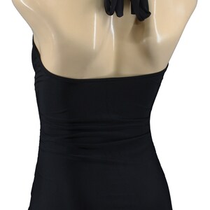 May include: Black halter-style swimsuit with a simple design. The swimsuit has a low back and a high leg cut.