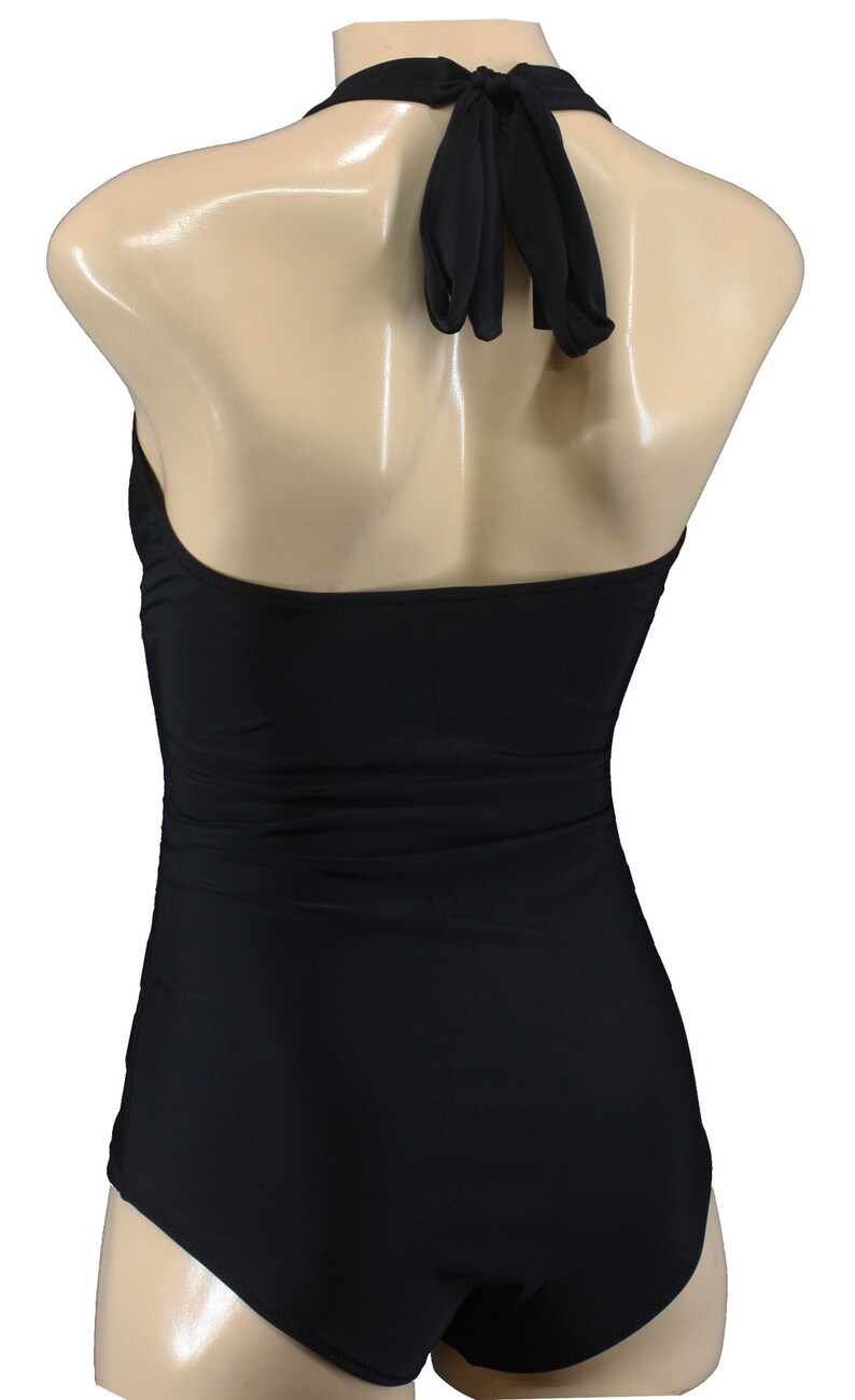 May include: Black halter-style swimsuit with a simple design. The swimsuit has a low back and a high leg cut.