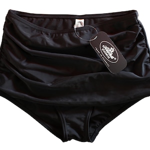 Peut inclure: Bas de maillot de bain noir taille haute avec un design froncé. Une étiquette noire avec le texte "Aloha Beachwear" est attachée. Le bas est fait d'un tissu lisse et brillant.