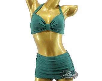 May include: A green halter-style bikini top with a bow detail and matching high-waisted skirt. The bikini is on a gold mannequin.