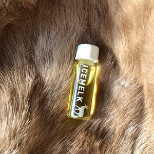May include: A small, clear glass bottle with a white cap. The bottle is filled with a yellow liquid and has the word "ICEMELK" printed on the side in white letters. A white deer silhouette is also printed on the bottle.