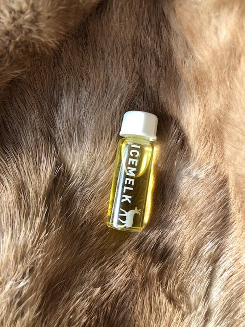 May include: A small, clear glass bottle with a white cap. The bottle is filled with a yellow liquid and has the word "ICEMELK" printed on the side in white letters. A white deer silhouette is also printed on the bottle.