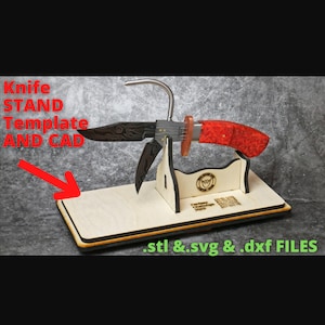 Puede incluir: Un soporte de madera para cuchillo con un cuchillo rojo y negro. El soporte tiene un gancho para sujetar el cuchillo en su lugar. El soporte está hecho de madera y tiene un acabado natural. El soporte está diseñado para sujetar un cuchillo con una longitud de hoja de hasta 25 cm. El soporte también es compatible con otros tipos de cuchillos, como cuchillos de bolsillo y cuchillos de caza. El soporte es una excelente manera de exhibir tus cuchillos favoritos y mantenerlos organizados. .stl & .svg & .dxf FILES