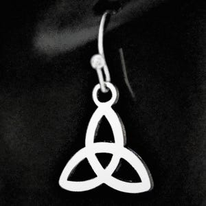 May include: A silver Celtic Trinity Knot earring. The earring has a three-leaf clover design, suspended from a hook. The background is a solid black.