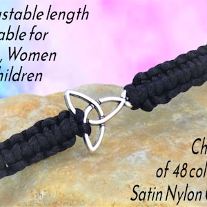 May include: Black satin nylon cord bracelet with a silver Celtic knot charm. The bracelet is adjustable and suitable for all ages. The image text says "Choice of 48 colours".