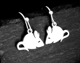May include: A pair of silver-toned drop earrings featuring flat, silhouette-style mouse charms. Each mouse charm has a simple, rounded body, pointed ears, and a curved tail, suspended from standard silver-toned earring hooks with small ball accents.