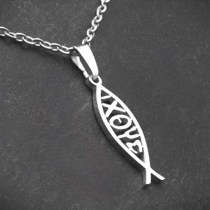 May include: A silver chain necklace with a silver pendant shaped like a fish with the word "XOYE" inscribed inside.