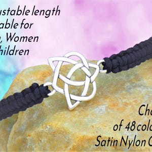 May include: A black satin nylon cord bracelet with a silver Celtic knot centerpiece. The bracelet has an adjustable length. The image also includes the text "Choice of 48 colours".