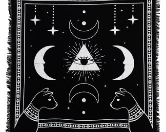 May include: Black and white tapestry with a mystical design featuring an all-seeing eye inside a triangle, surrounded by crescent moons and stars. Two stylized cats flank the design.